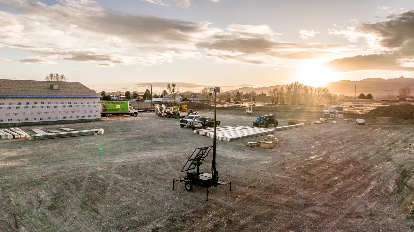Drone view of an Overwatch trailer standing watch over a commercial construction site, with the building and laydown yard behind it.