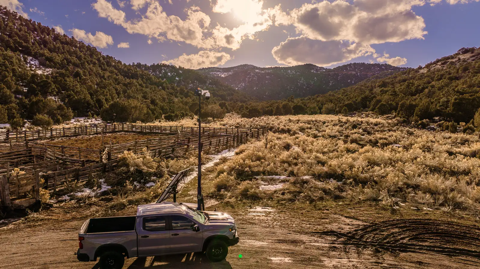 A pickup truck parked beside an Overwatch trailer deployed on open ranch land, seen from above.