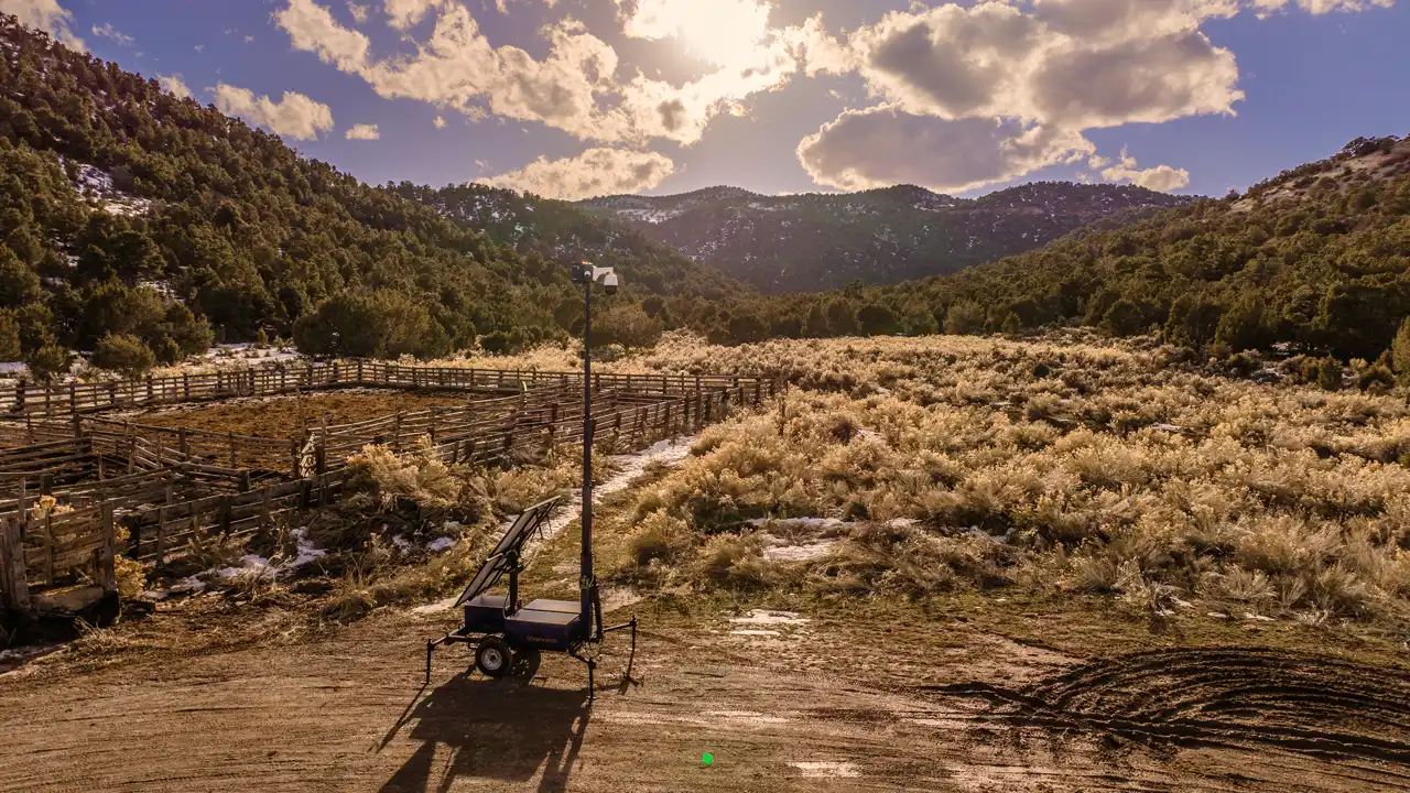 An Overwatch trailer deployed on open ranch land, mast raised, mountains behind.